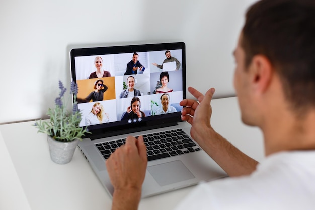 Persona que usa tecnología de videoconferencia en la cocina para videollamadas con colegas en casa y en la oficina