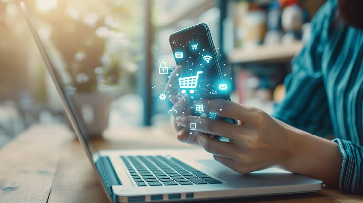 Persona que utiliza un teléfono inteligente junto a una computadora portátil
