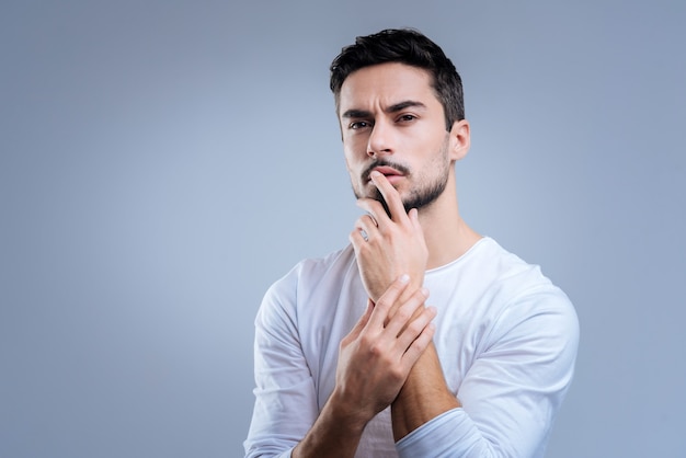 Persona reflexiva. Persona creativa pacífica tranquila de pie con la mano cerca de los labios