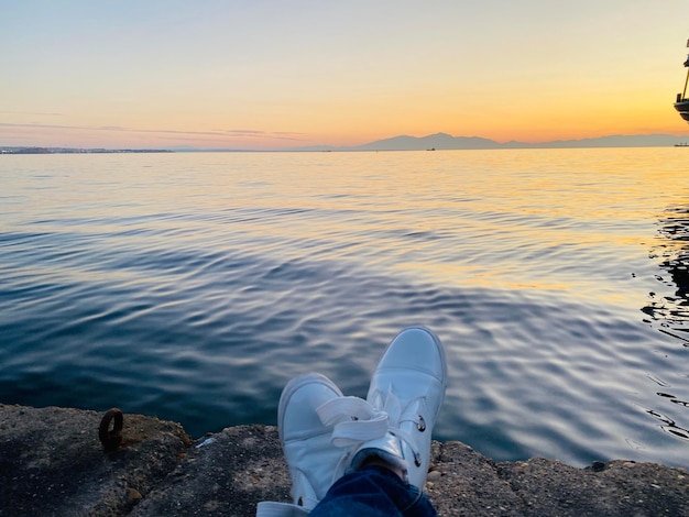 Foto una persona está sentada en una roca con vistas al agua