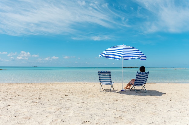 Persona sentada en una silla en una playa tropical