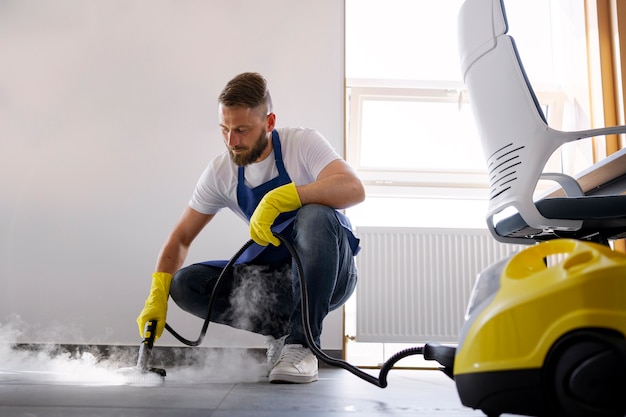 Foto persona de servicio de limpieza profesional que usa limpiador de vapor en la oficina