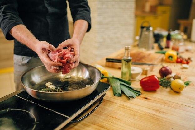 Persona del sexo masculino cocinar carne con hierbas en una sartén