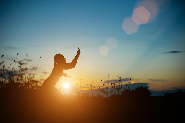 Foto persona en silueta de pie en el campo contra el cielo durante la puesta de sol