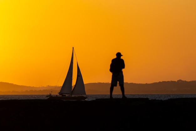 Una persona en silueta se ve en el muelle de Porto da Barra contra la puesta de sol en la ciudad de Salvador Bahia