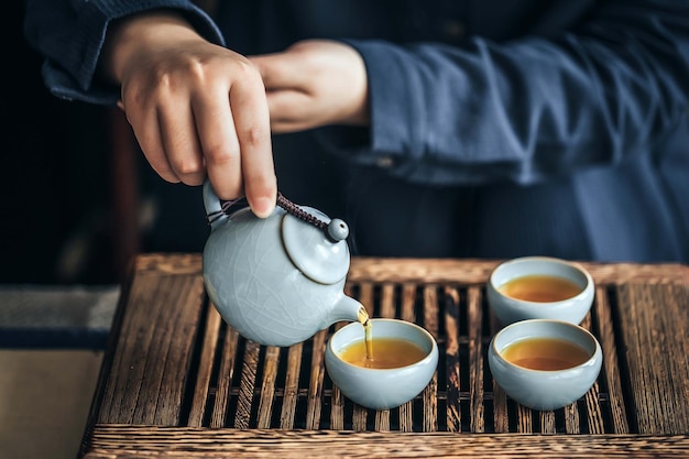 Una persona sirviendo té en tazas.