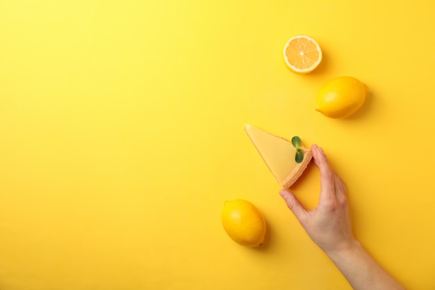 Persona sostenga una rodaja de tarta de limón en amarillo, vista superior