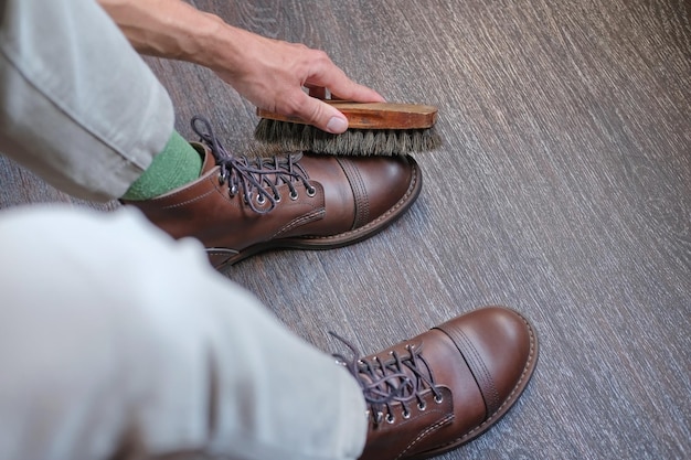 Foto persona sosteniendo un cepillo para zapatos y limpiando y cepillando un par de zapatos