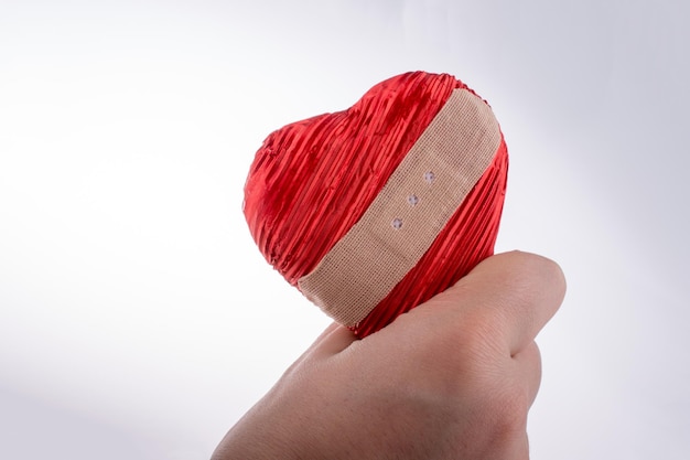 Foto una persona sosteniendo un corazón con una venda en la mano.