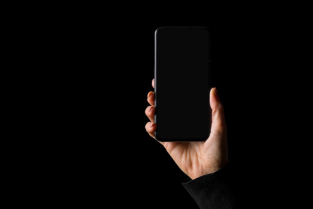 Persona sosteniendo en la mano smartphone aislado sobre fondo negro