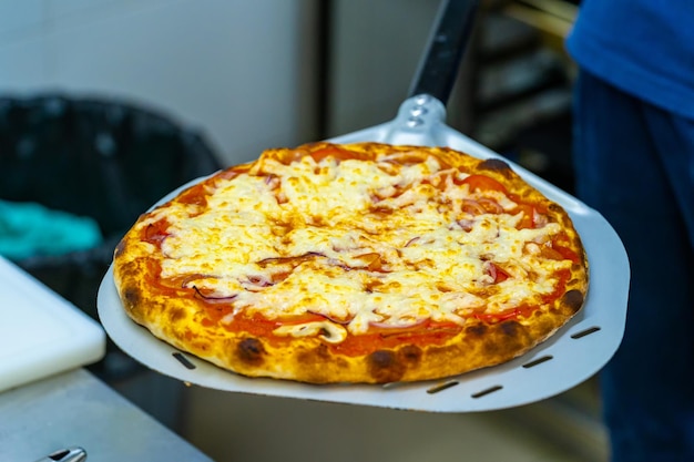 Una persona sosteniendo una pizza con queso