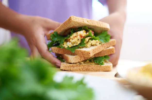 Una persona sosteniendo un sándwich con ensalada de huevo.