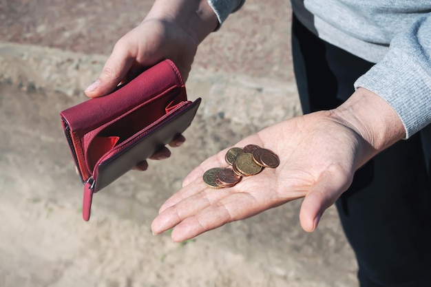 Una persona sostiene una billetera con monedas en la mano.