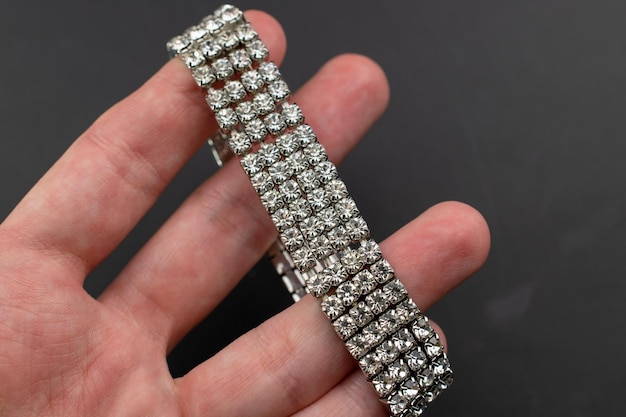 una persona sostiene un brazalete de plata con diamantes en él