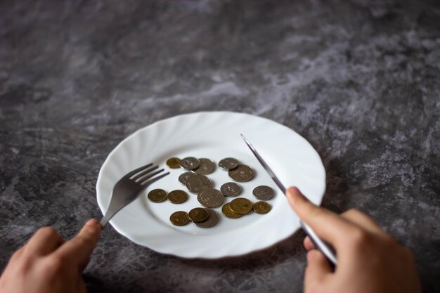 Una persona sostiene un cuchillo y un plato con monedas.