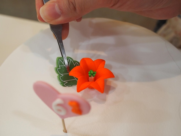 Una persona sostiene un tenedor y un pastel con una flor.