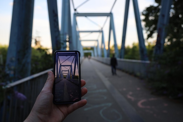 Foto persona con un teléfono móvil y tomando una foto de un puente