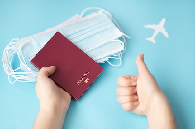 Persona titular de un pasaporte con mascarillas quirúrgicas sobre un fondo azul.