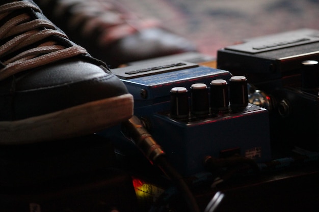 Foto persona tocando la guitarra con el pie en la pedalera de guitarra.