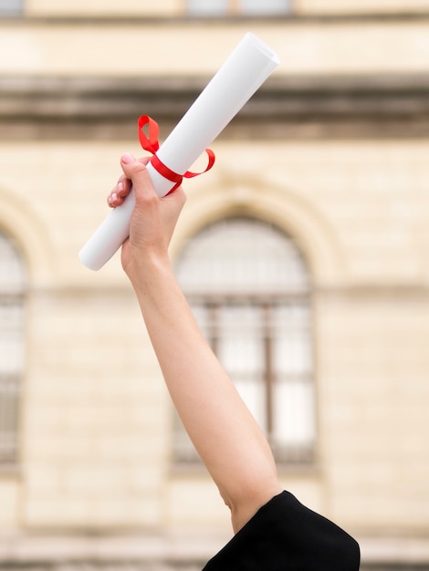 Foto persona en toga de graduación sosteniendo un diploma