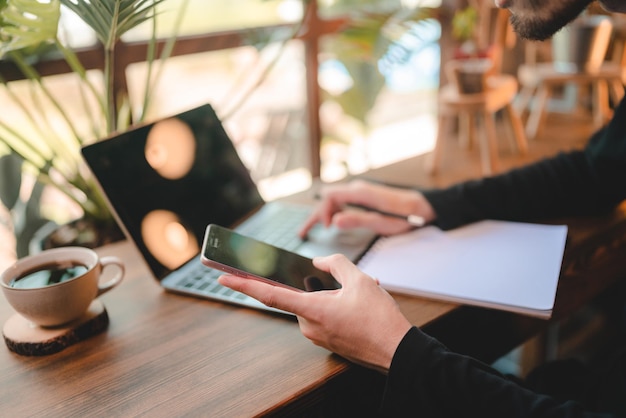 Persona de trabajador de negocios que trabaja en la cafetería mediante el uso de una computadora portátil en la tecnología de comunicación en línea