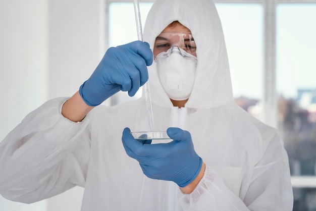 Foto persona con traje de prevención y tomando muestras