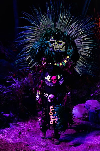 Foto persona vestida para el día de muertos con traje prehispánico de neón reflejos nocturnos