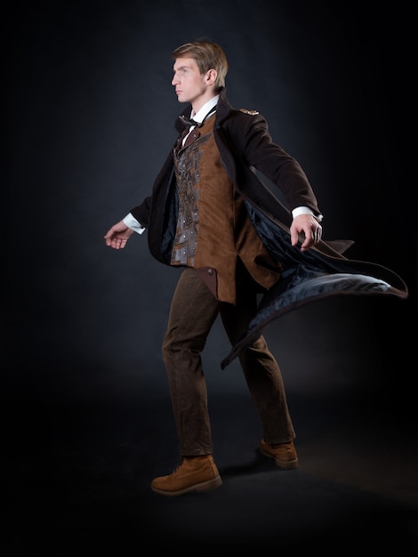 Personagem da história steampunk, jovem atraente em um elegante casaco longo, aventureiro faz um gesto épico. cavalheiro inteligente em estilo vitoriano. Terno retro vintage, jovem atraente