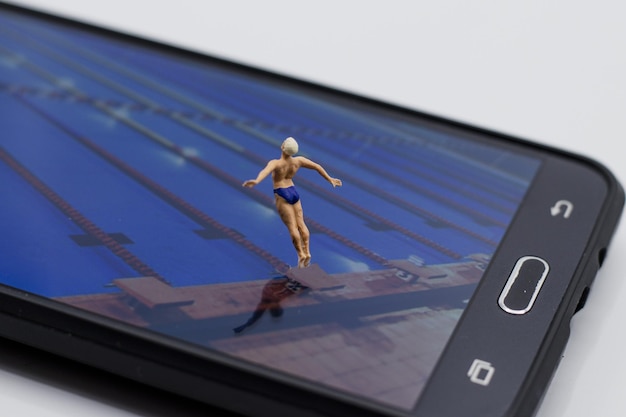 Personagem em miniatura na tela de um smartphone se preparando para pular na piscina