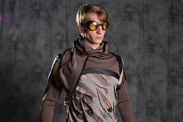 Personaje de estilo steampunk o post-apocalíptico, un hombre joven con un traje grunge. Una chaqueta con mangas abrochadas con aberturas m gafas de vuelo en la cabeza, un traje grunge