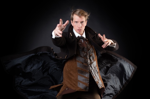 Personaje de historia steampunk, joven atractivo con un elegante abrigo largo, aventurero hace un gesto épico. caballero inteligente en estilo victoriano. Traje retro vintage, joven atractivo
