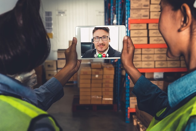 El personal del almacén hablando por videollamada en la pantalla de la computadora en el almacén de almacenamiento