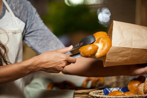 Personal, das Brot in Papiertüte an Bäckerei verpackt