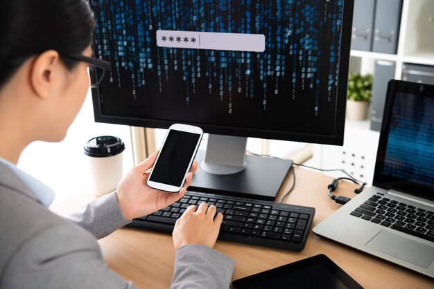 el personal de la empresa de seguridad cibernética sostiene un teléfono celular y lee el mensaje de queja del cliente y escribe en el teclado para ingresar a la computadora