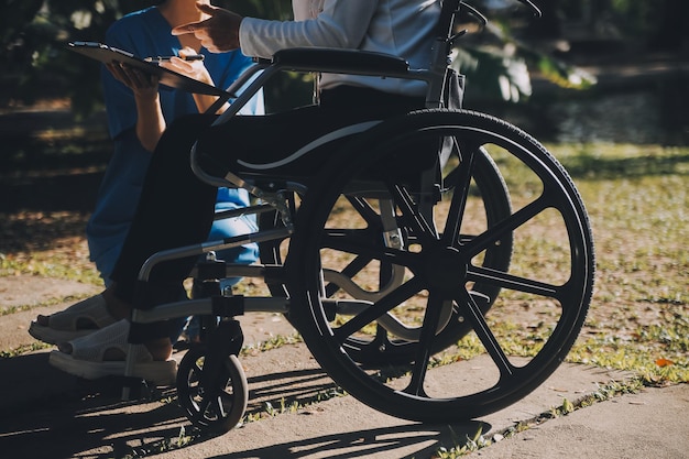 Personal de enfermería hablando con una persona mayor sentada en silla de ruedas