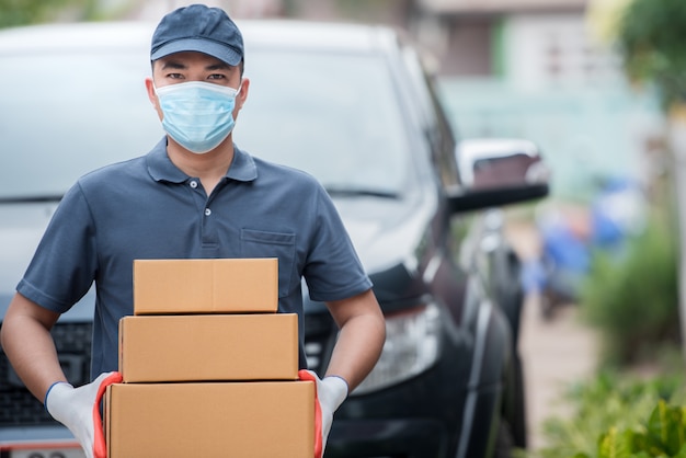 Personal de entrega llevando cajas de papel. Use guantes y máscaras médicas para proteger Covid-19