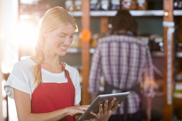 Personal femenino con tableta digital en supermercado