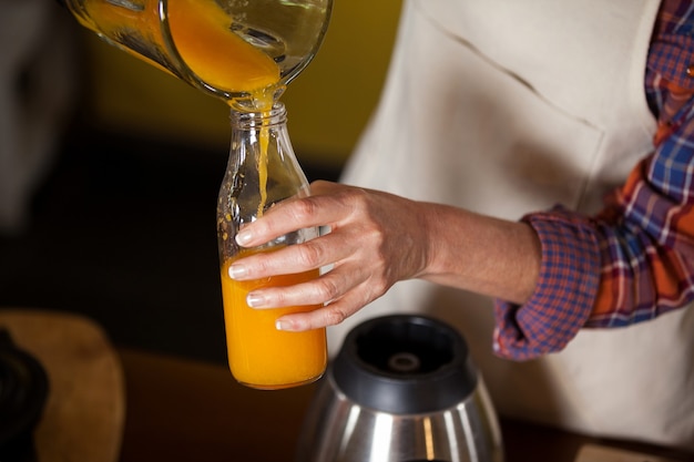 Personal femenino vertiendo jugo en una botella