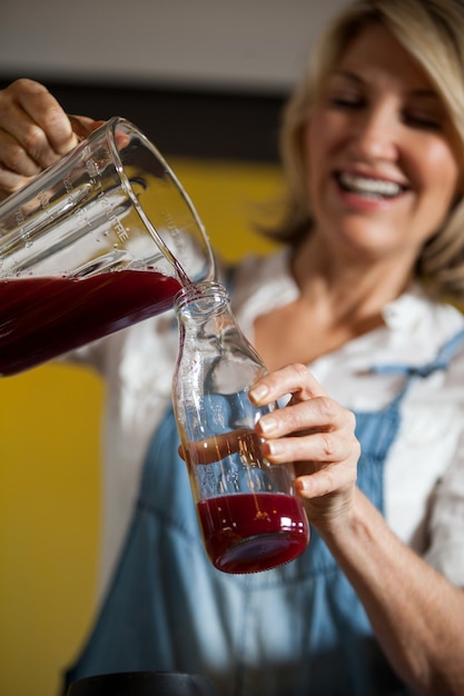 Personal femenino vertiendo jugo en una botella