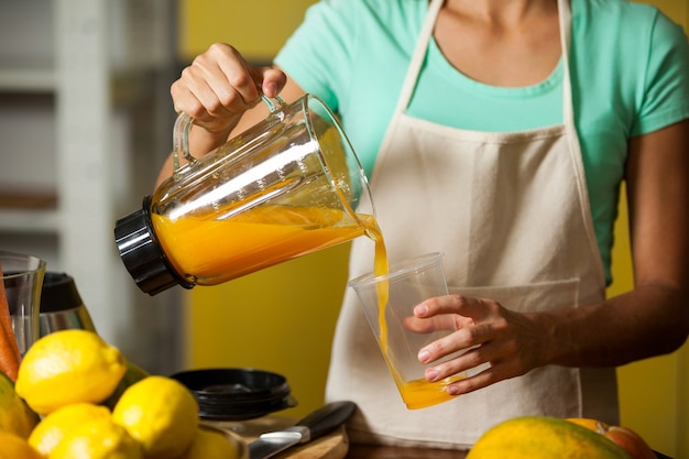 Personal femenino vertiendo jugo en vaso en el mostrador