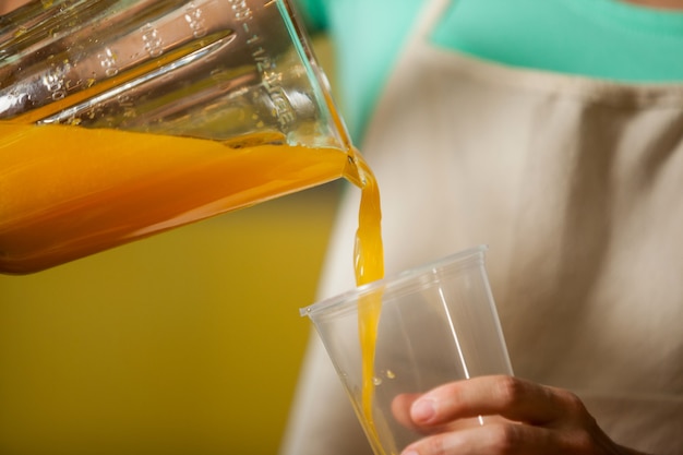 Personal femenino vertiendo jugo en vaso en el mostrador