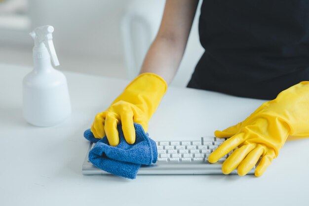 Foto el personal de limpieza limpia el equipo de oficina limpie el teclado con una toalla y desinfectante use guantes de goma cuando trabaje con productos químicos de limpieja