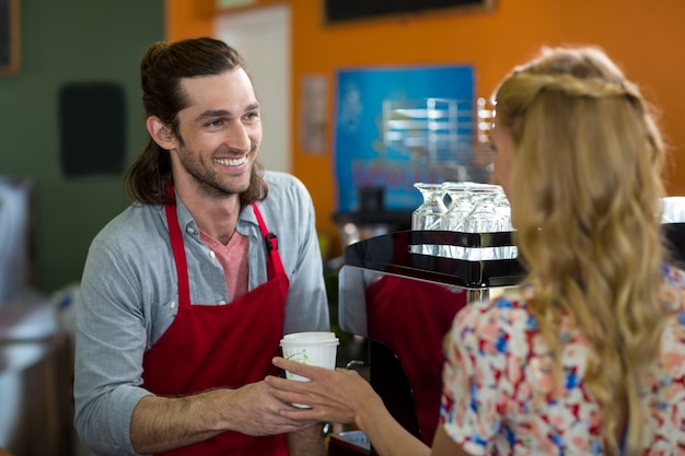 Personal masculino dando café a la mujer en la cafetería.