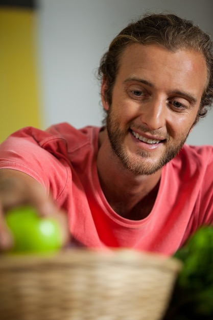 Personal masculino sonriente arreglando frutas en la sección orgánica