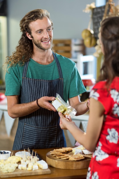 Personal masculino sonriente dando paquete a la mujer en el mostrador