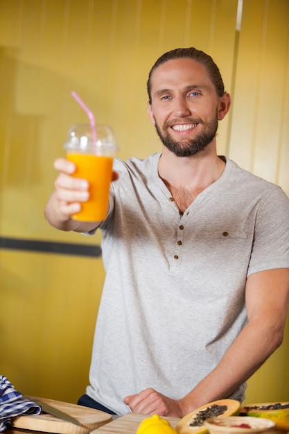 Personal masculino con vaso de jugo de naranja en la sección orgánica