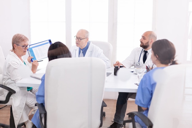 El personal médico se reunió en la sala de conferencias para hablar sobre la enfermedad del paciente. Terapeuta experto de la clínica hablando con colegas sobre el tratamiento, profesional de la medicina