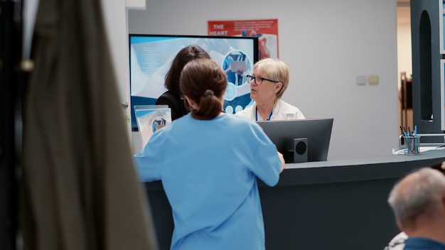 Foto personal médico y secretaria hablando en la recepción del hospital, trabajando en el servicio de información administrativa en el vestíbulo de la clínica. recepcionista y médico charlando en la sala de espera.