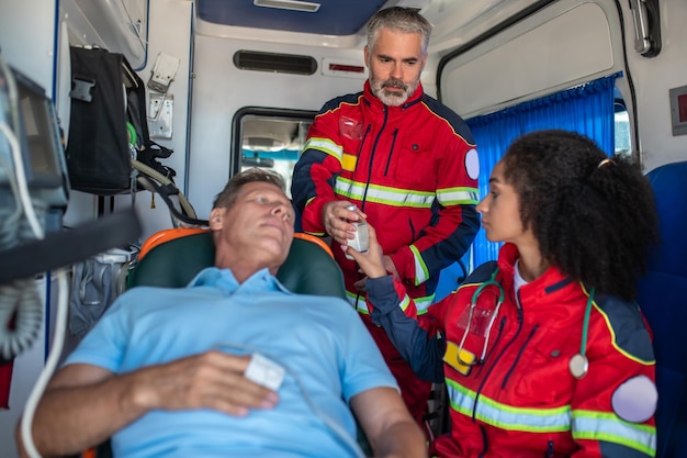 Personal paramédico preparando al hombre para el goteo intravenoso