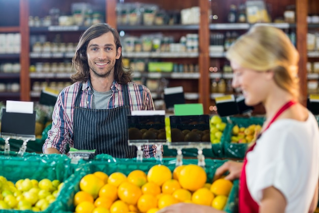 Personal sonriente que controla frutas en la sección orgánica